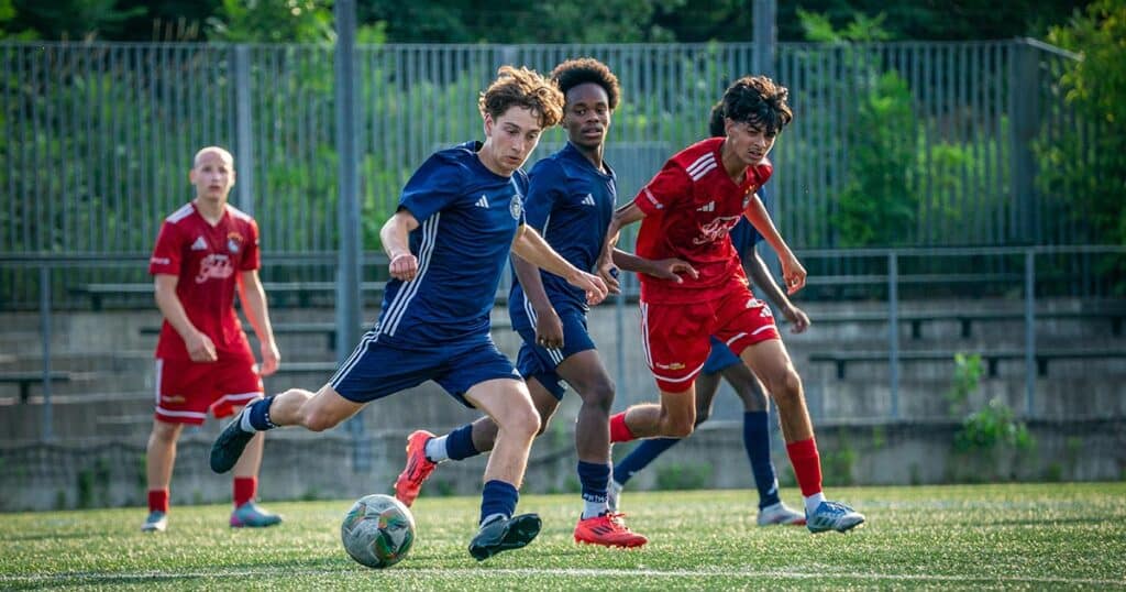 A boy kicking a soccer ball during a game while wearing clear aligners for teens