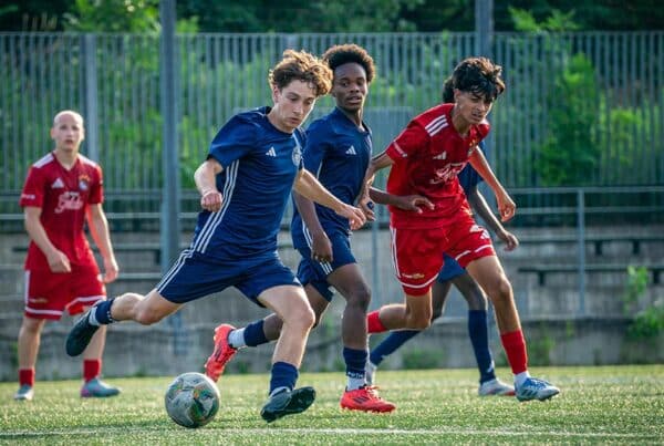 A boy kicking a soccer ball during a game while wearing clear aligners for teens