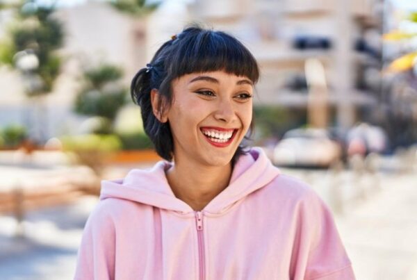 A girl in a pink hoodie smiling for a blog post titled, "Are Your Teeth Supposed to Touch?"